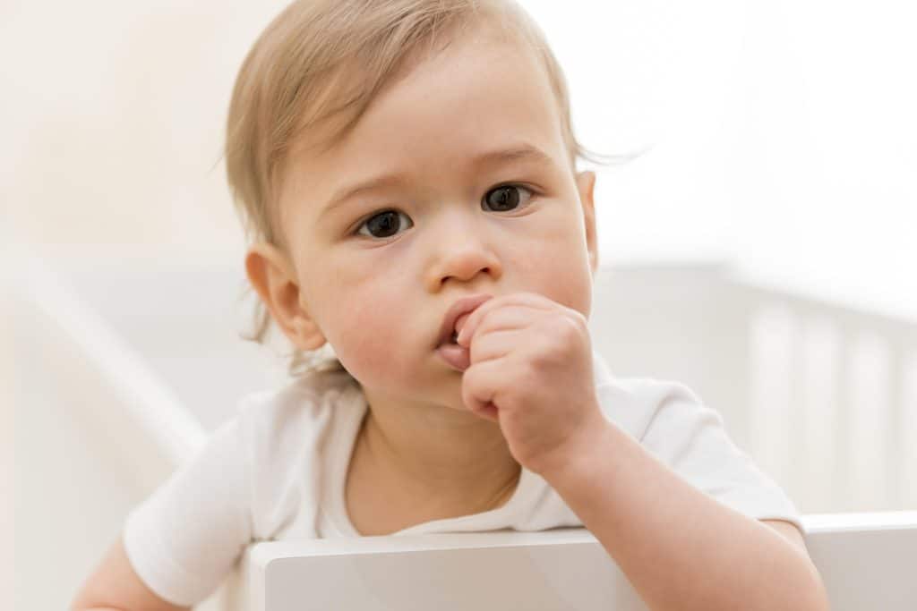 Baby met vinger in de mond tijdens het doorkomen van tandjes, een moment waarop ouders zich afvragen vanaf welke leeftijd tandarts nodig is.